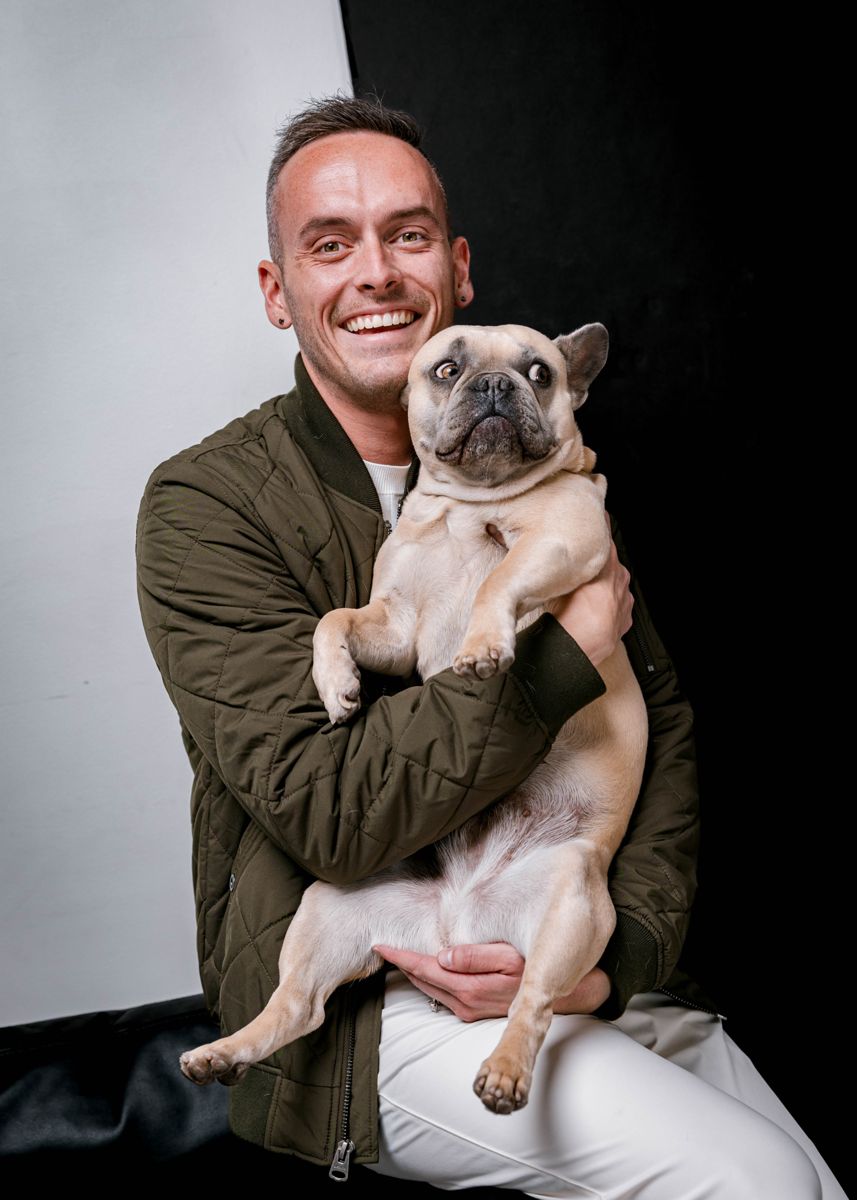 Tyler holding his fawn French bulldog and laughing