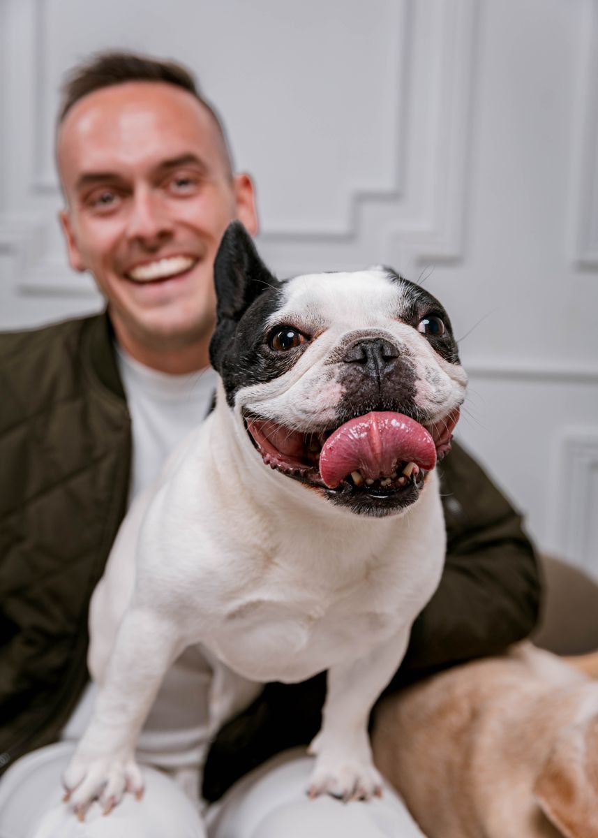 Tyler smiling beside his black and white French bulldog