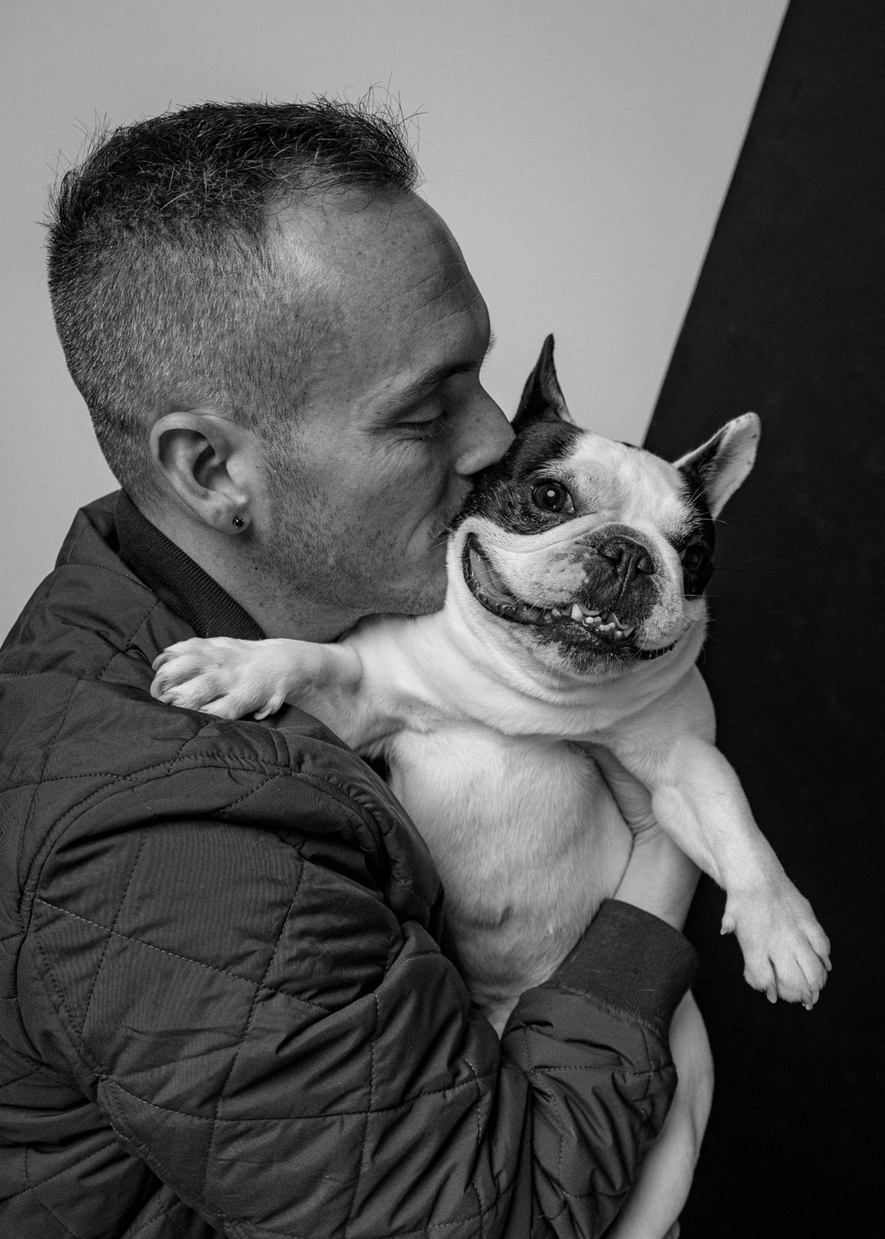 Tyler kissing his black and white French bulldog